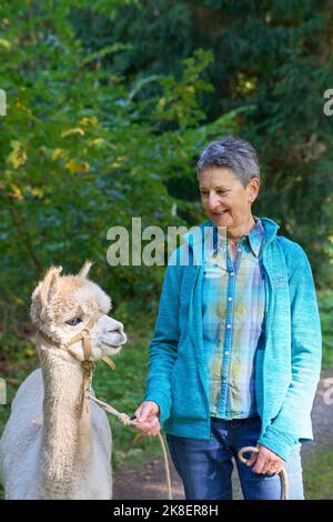 Un Sunbeam rencontre une femme avec beige Alpaca sur Forest Path. Dans la Forêt verte de fond. Bauma, Oberland de Zurich, Suisse Banque D'Images