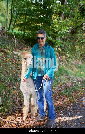 Un Sunbeam rencontre une femme avec beige Alpaca sur Forest Path. Dans la Forêt verte de fond. Bauma, Oberland de Zurich, Suisse Banque D'Images