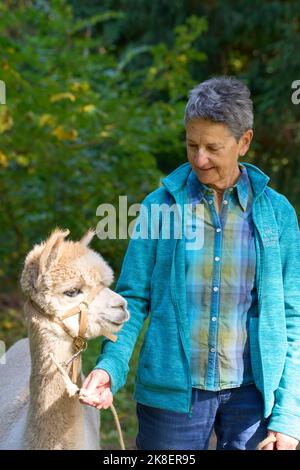 Un Sunbeam rencontre une jeune femme avec beige Alpaca sur Forest Path. Dans la Forêt verte de fond. Bauma, Oberland de Zurich, Suisse Banque D'Images