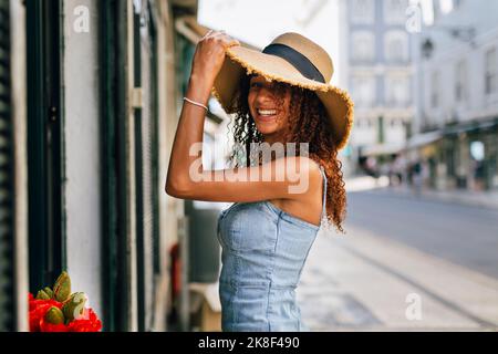 Jeune femme heureuse avec cheveux bouclés portant un chapeau Banque D'Images