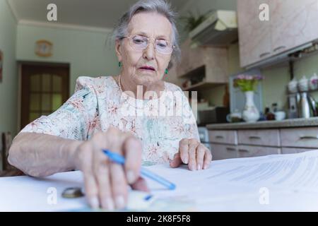Femme âgée comptant de l'argent et faisant de la paperasserie à la maison Banque D'Images