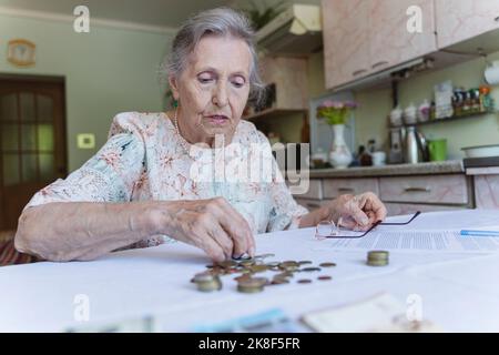 Femme âgée comptant les économies et faisant de la paperasserie à la maison Banque D'Images