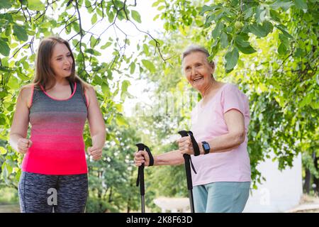 Instructeur de fitness enseignant l'exercice à une femme âgée avec un poteau de marche dans le parc Banque D'Images