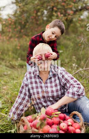 Garçon joueur tenant des pommes au-dessus des yeux des grands-mères à la ferme Banque D'Images