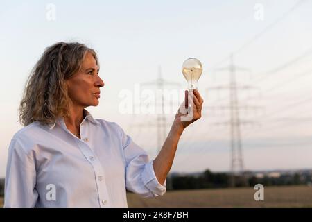 Femme sénior qui regarde l'ampoule Banque D'Images