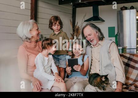 Une fille partageant un Tablet PC avec ses grands-parents et ses frères et sœurs à la maison Banque D'Images