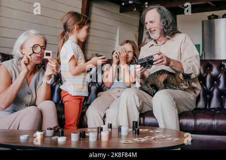 Petites-filles avec grands-parents regardant un appareil photo de film d'époque et des diapositives de film Banque D'Images