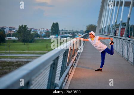 Femme mature qui étire les jambes debout sur le pont Banque D'Images