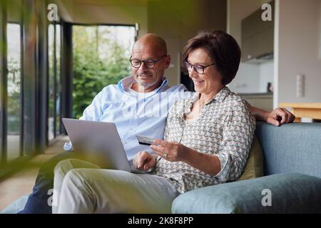 Un couple heureux effectuant le paiement par carte de crédit sur ordinateur portable à la maison Banque D'Images