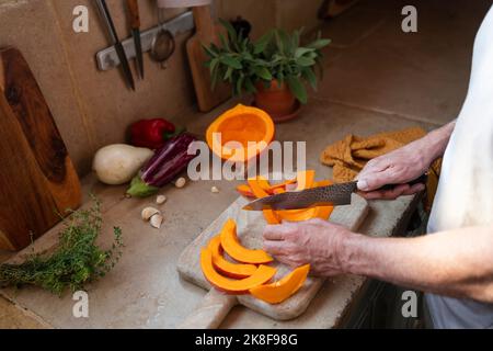 Mains de l'homme coupant de la citrouille à bord dans la cuisine Banque D'Images