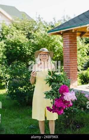 Femme tenant des sécateurs et des fleurs dans le jardin Banque D'Images