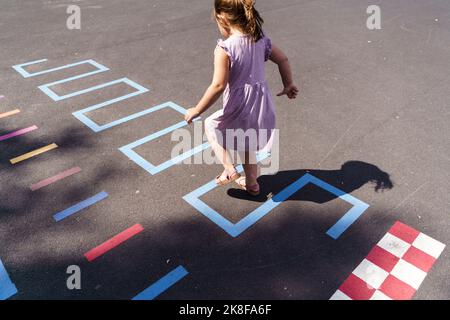 Fille jouant au hopscotch à l'aire de jeux Banque D'Images