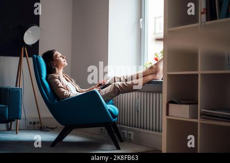 Femme d'affaires se détendant sur une chaise à la maison Banque D'Images