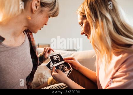 Femme discutant à la maison d'une échographie avec une sœur enceinte Banque D'Images