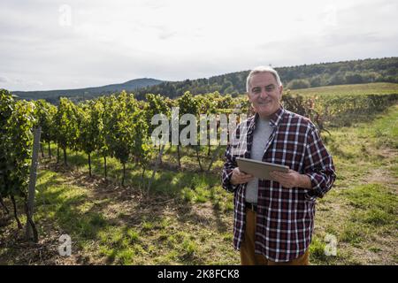 Éleveur souriant avec une tablette PC dans un vignoble Banque D'Images