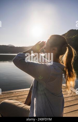 Femme faisant du yoga avec les mains jointes en vacances Banque D'Images