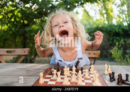 Fille excitée avec échiquier sur la table dans le jardin Banque D'Images