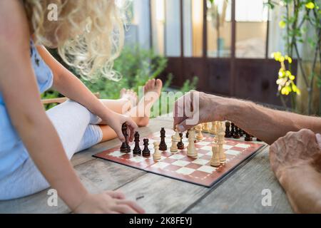Mains de grand-père jouant aux échecs avec la petite-fille sur la table Banque D'Images