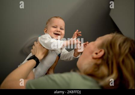 La mère soulève bébé fille heureux à la maison Banque D'Images