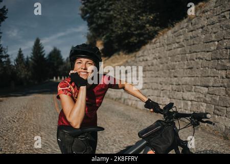 Femme souriante portant un casque assis sur un siège de vélo Banque D'Images