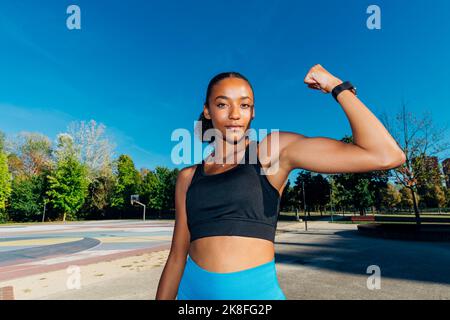 Un jeune athlète en flexion de biceps sur un terrain de basket-ball Banque D'Images