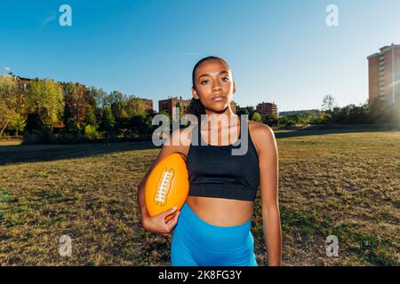 Joueur de football américain confiant avec ballon de sport sur le terrain Banque D'Images