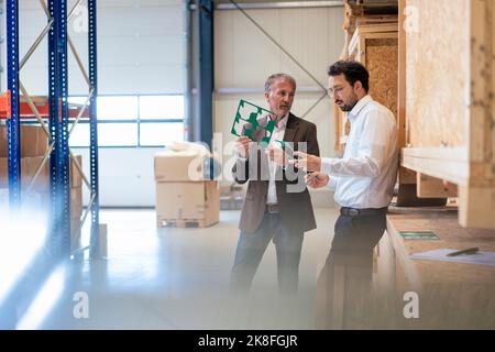 Hommes d'affaires examinant la commission mère dans l'entrepôt Banque D'Images