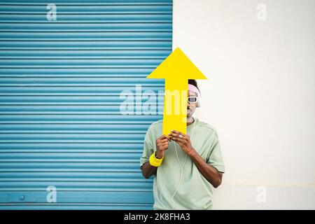 Homme couvrant le visage avec une flèche jaune devant le mur par le volet Banque D'Images