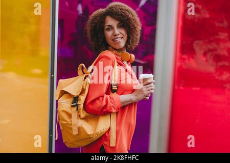 Jeune femme avec une tasse à café jetable au milieu de verres colorés Banque D'Images