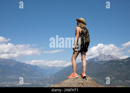 Femme âgée portant un chapeau debout sur le rocher en face des montagnes Banque D'Images