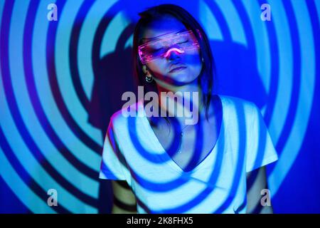 Ombre en spirale sur une jeune femme portant des lunettes LED intelligentes Banque D'Images