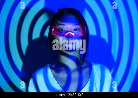Ombre en spirale sur une jeune femme portant des lunettes LED futuristes Banque D'Images