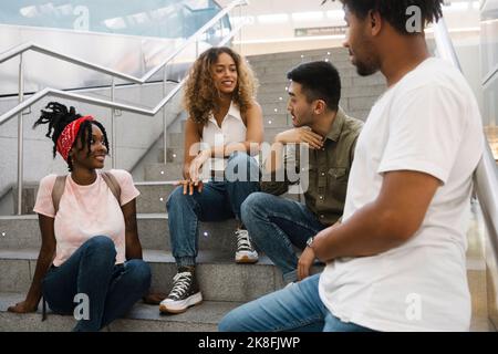 Jeune homme parlant à des amis multiraciaux dans l'escalier Banque D'Images