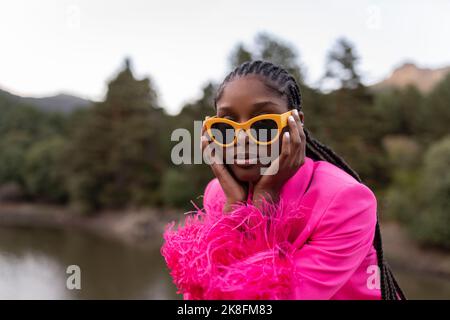 Jeune femme aux cheveux tressés portant des lunettes de soleil Banque D'Images