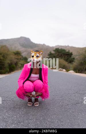 Jeune femme portant un masque tigre qui croque sur la route Banque D'Images