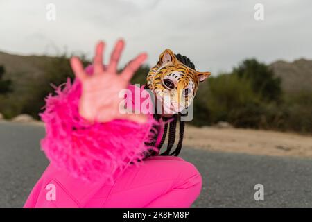 Jeune femme portant un masque tigre montrant un geste d'arrêt avec la main Banque D'Images