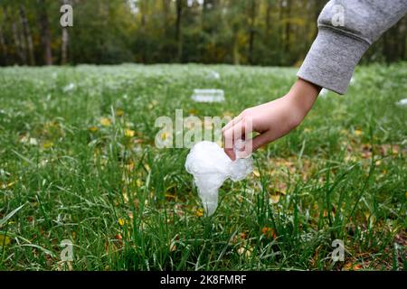 Main du garçon ramassant le plastique de l'herbe Banque D'Images
