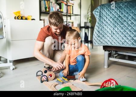 Père et fils jouant avec un mini train à la maison Banque D'Images