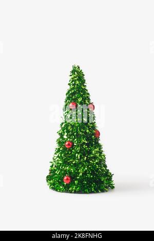 Petit arbre de noël en confettis verts et boules rouges sur fond blanc Banque D'Images