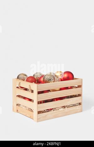 Boîte en bois pleine de boules de noël colorées sur fond blanc Banque D'Images