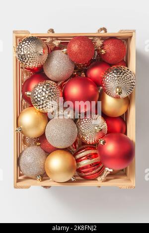 Boîte en bois avec boules de noël brillantes sur fond blanc Banque D'Images