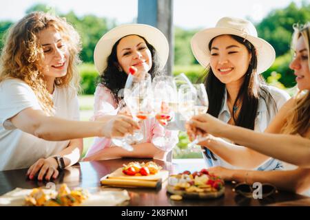 Des amis qui toaster des verres de vin assis à table Banque D'Images