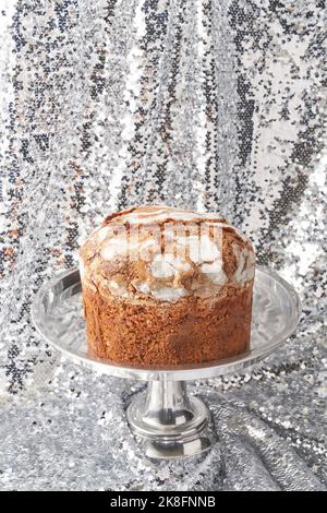 Gâteau panettone fraîchement cuit sur le cakestan contre des paillettes argentées brillantes Banque D'Images