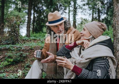 Femme avec homme âgé ayant le thé assis dans la forêt Banque D'Images