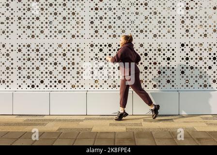 Femme de plus grande taille qui fait du jogging au mur Banque D'Images