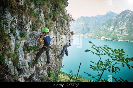 Fille avec frère montagne d'escalade avec le lac Idro en arrière-plan Banque D'Images