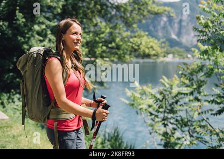 Jeune randonneur attentionné avec sac à dos et bâtons de randonnée Banque D'Images