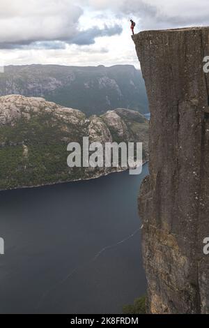 Randonneur debout sur le bord de la majestueuse falaise de Pulpit par le fjord Lysefjorden, Norvège Banque D'Images