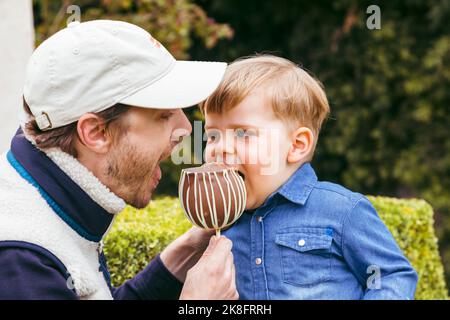 Père avec son fils mangeant de la pomme au caramel au parc Banque D'Images