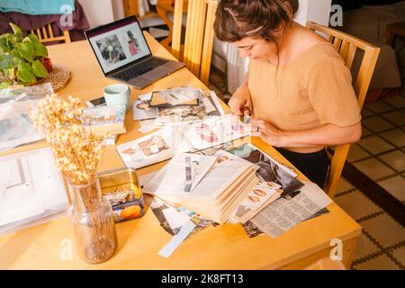 Graphiste collant des coupures de papier dans le livre travaillant à la maison Banque D'Images